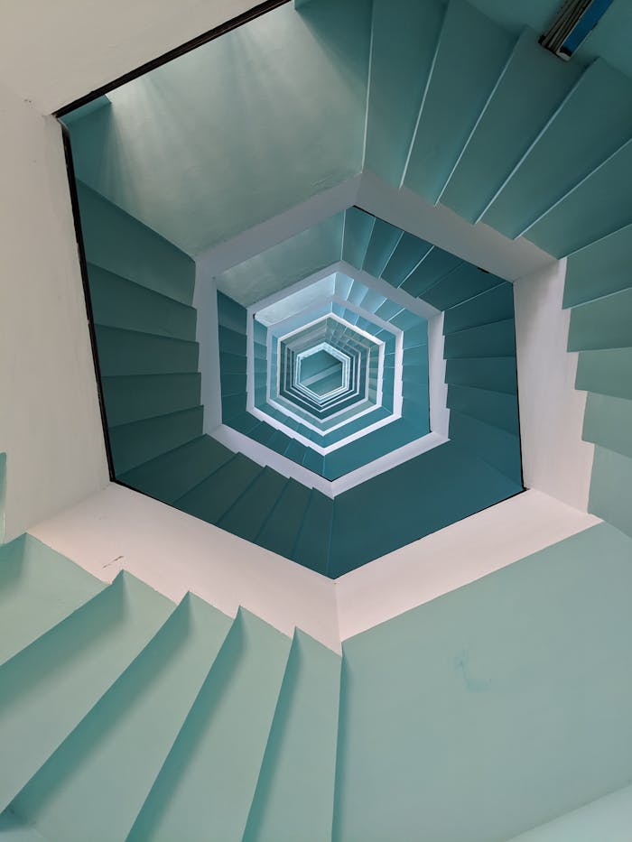 Services Vertical view of a geometric stairwell with a blue pattern in Puducherry, India.